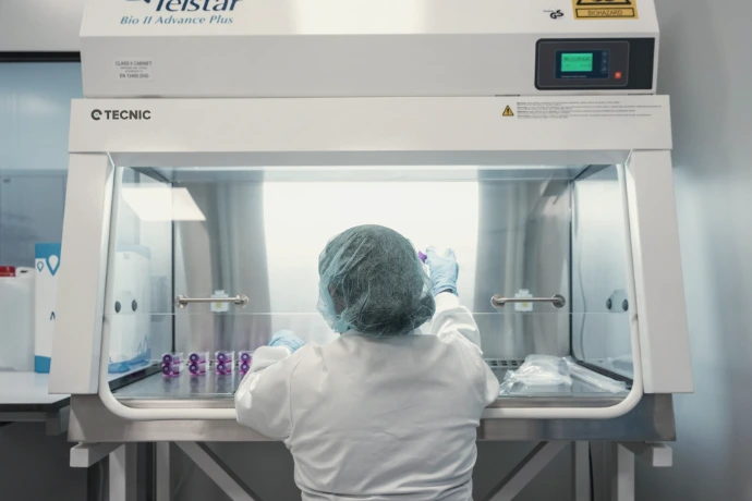 A scientist works in a lab hood, conducting research.